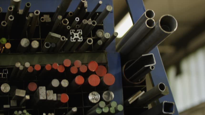 A variety of metal rods and tubes are organized on a blue storage rack