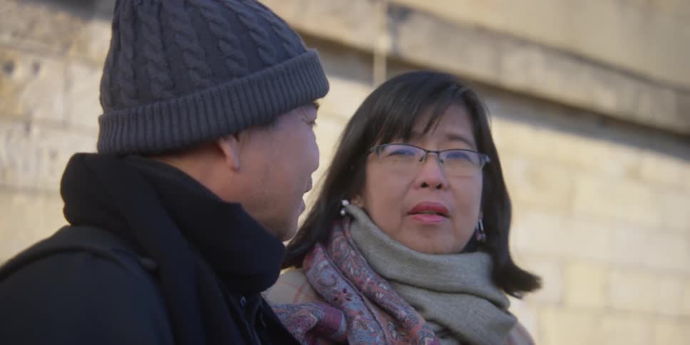 An asian couple laugh and smile while having a conversation