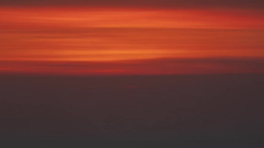 The sun is setting on the horizon and the whole sky is orange