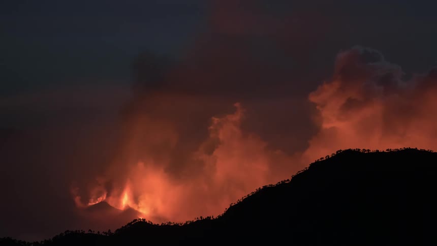 A volcano erupting with fire and releasing a lot of smoke