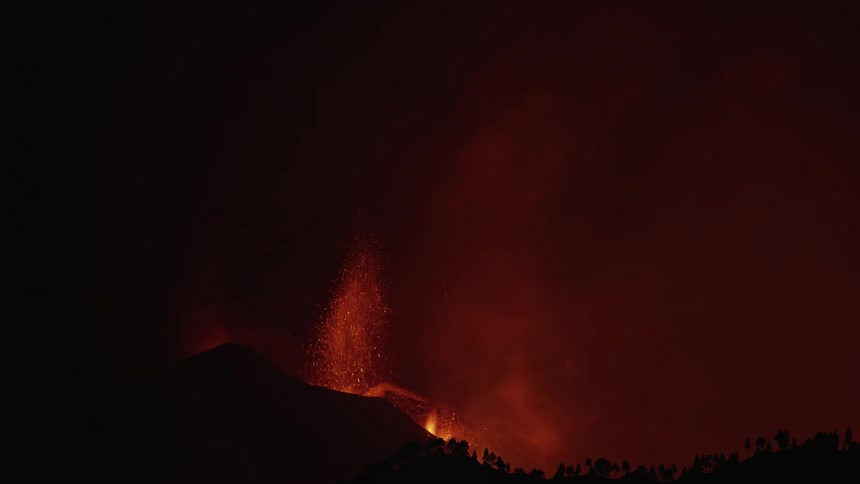 Lightening strikes beside orange volcano lava flames shooting up from mountain at night
