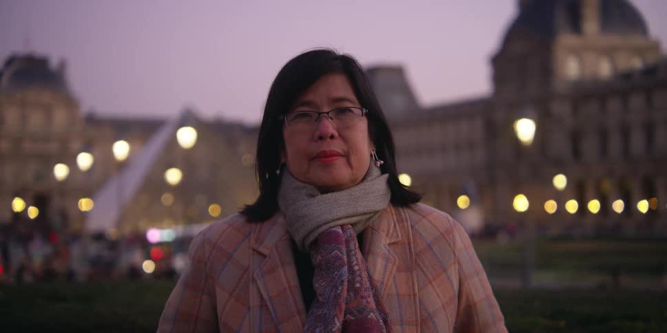 A woman standing outdoors in a city at sunset