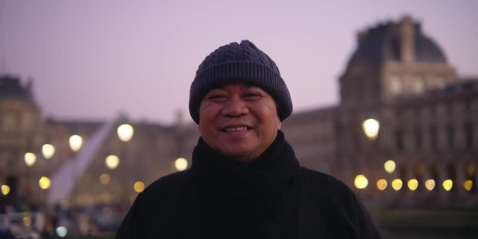 A smiling man in the center of a city at dusk
