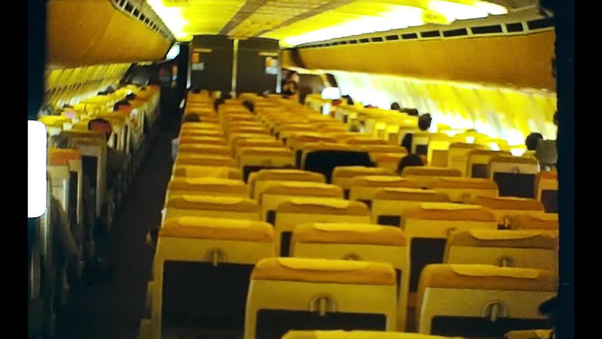 Airplane interior with rows of empty seats and some people seated far away