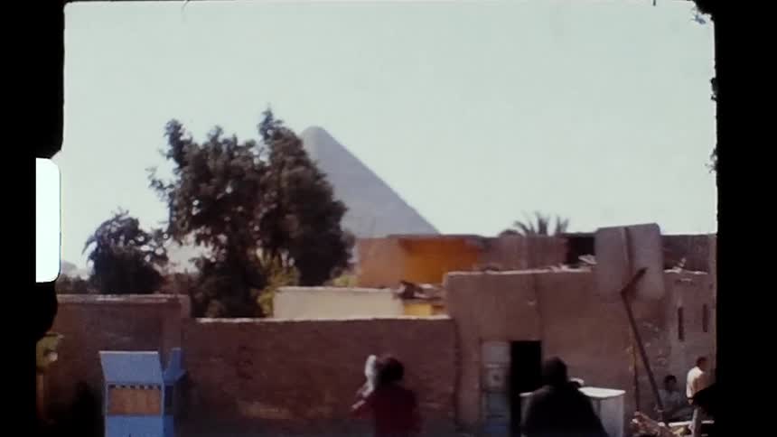 A pyramid is visible from an area with people walking around buildings