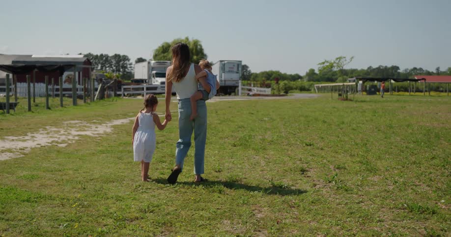 Mother walks hand in hand with daughter whilst holding a  baby