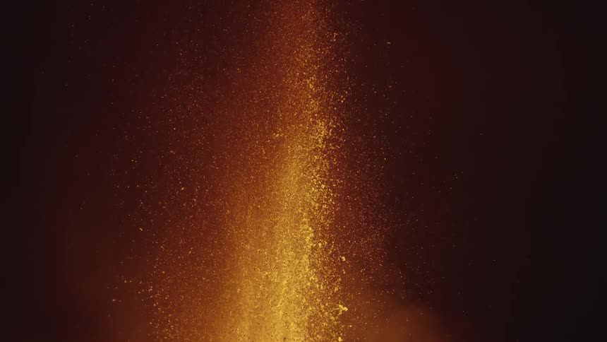 Close slow motion lava eruption spewing a fountain of orange flame and sparks at night