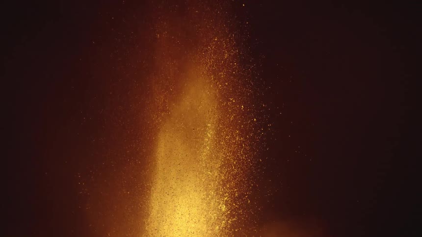 Close slow motion lava eruption spewing a fountain of orange flame and sparks at night
