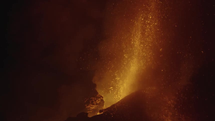 Hot magma glows as a volcano erupts and lava flies into the air