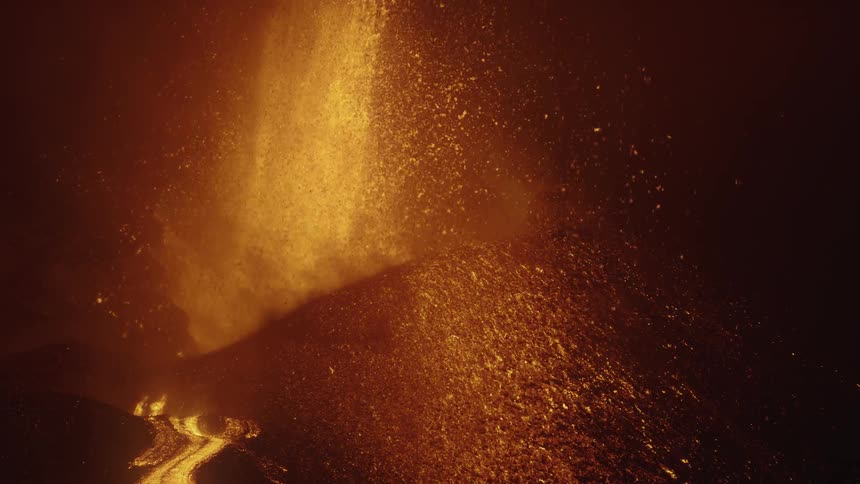 Hot glowing lava sprays into the air as a volcano erupts