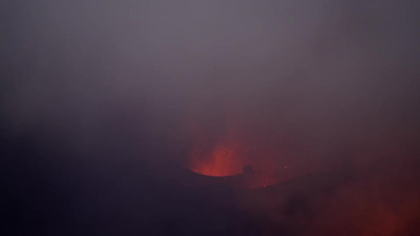 An erupting volcano releasing lava upwards and there is a lot of smoke in the environment