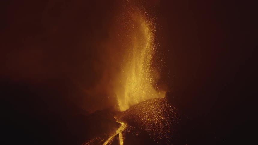 An erupting volcano splashing larva upward and it is falling down the mountain