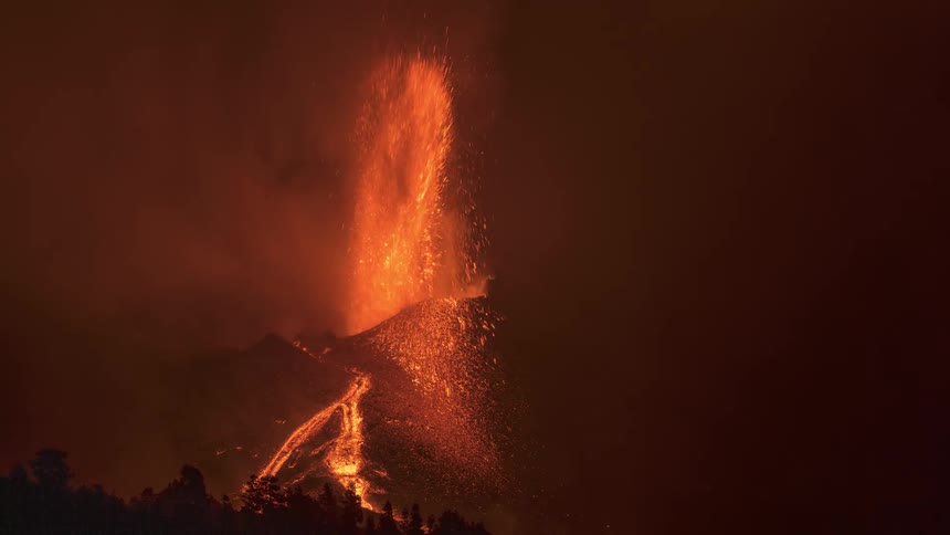 Timelapse volcanic eruption of orange flames shooting up from mountain with flowing lava river at night