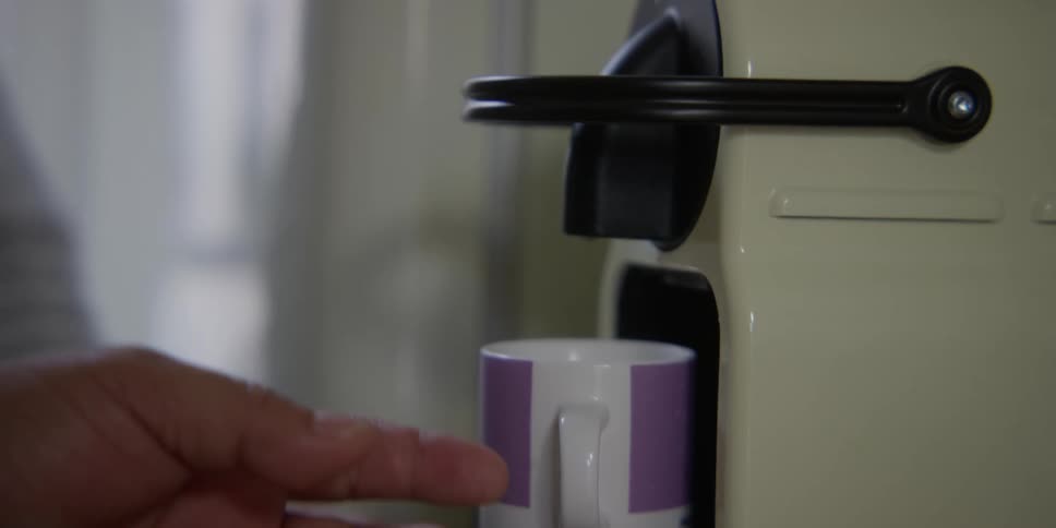 A person prepares two cups of coffee at home