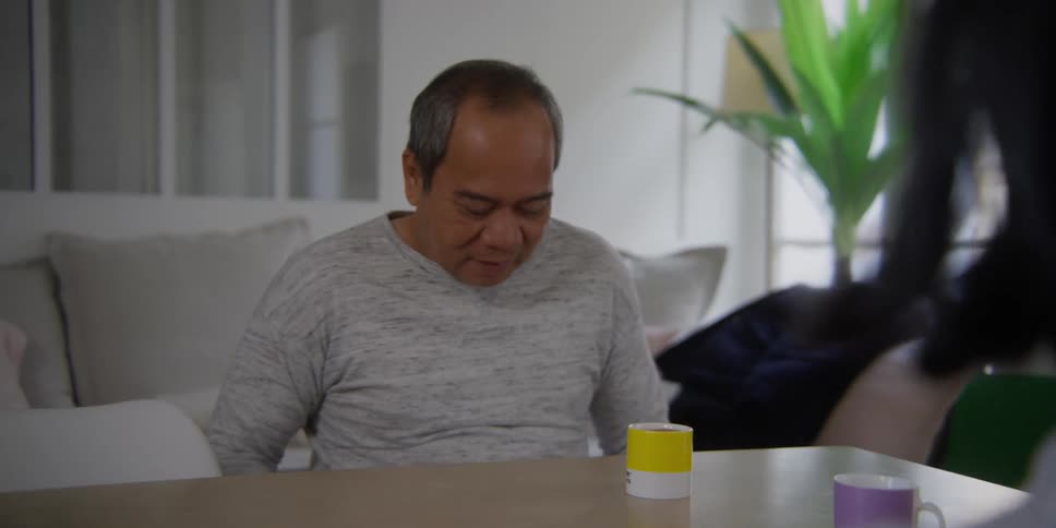 An asian man smiles after as he sits with his female companion at a table