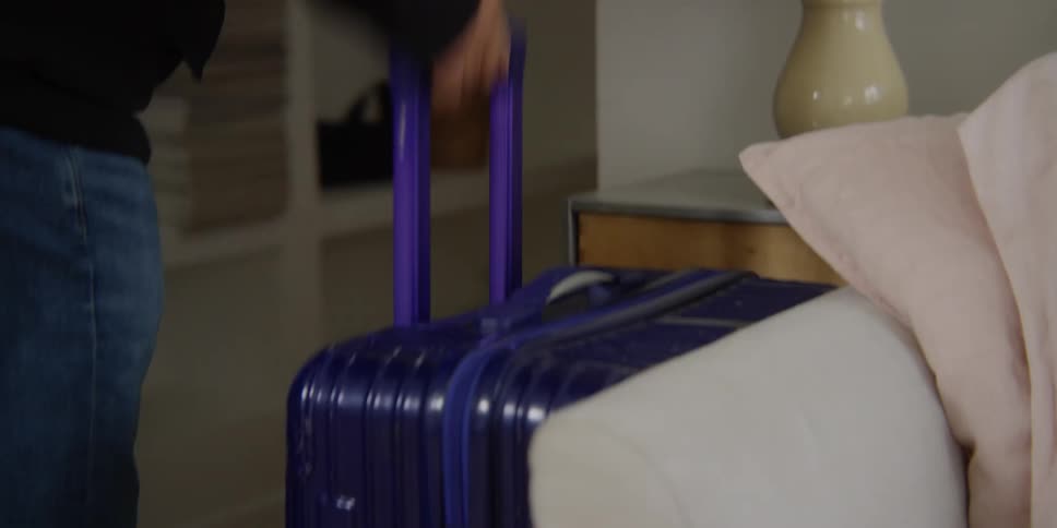 Older couple arriving in apartment with suitcase smile as they talk
