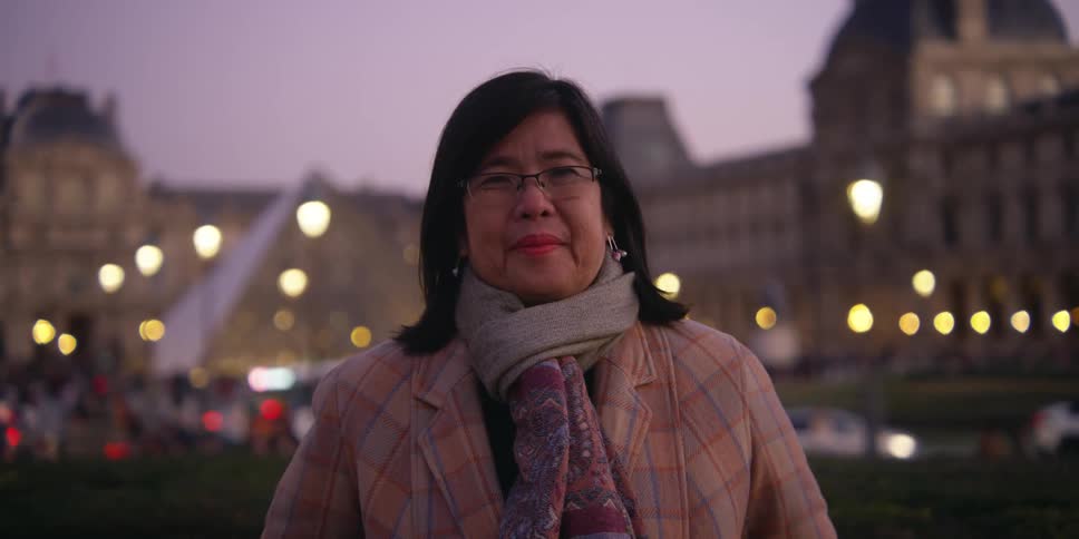An asian woman stands and poses in front of a busy city area
