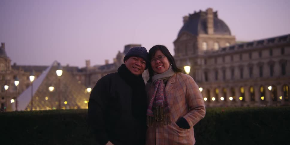 A couple smile in front of the palace