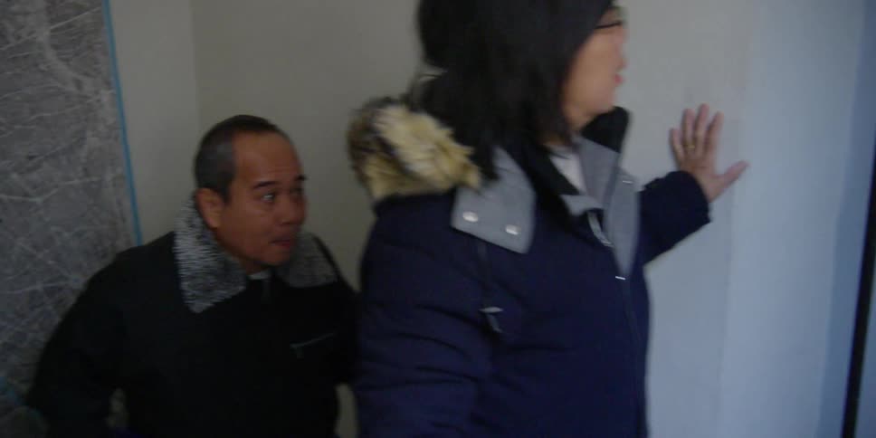An asian man and woman ascend a staircase to reach a door