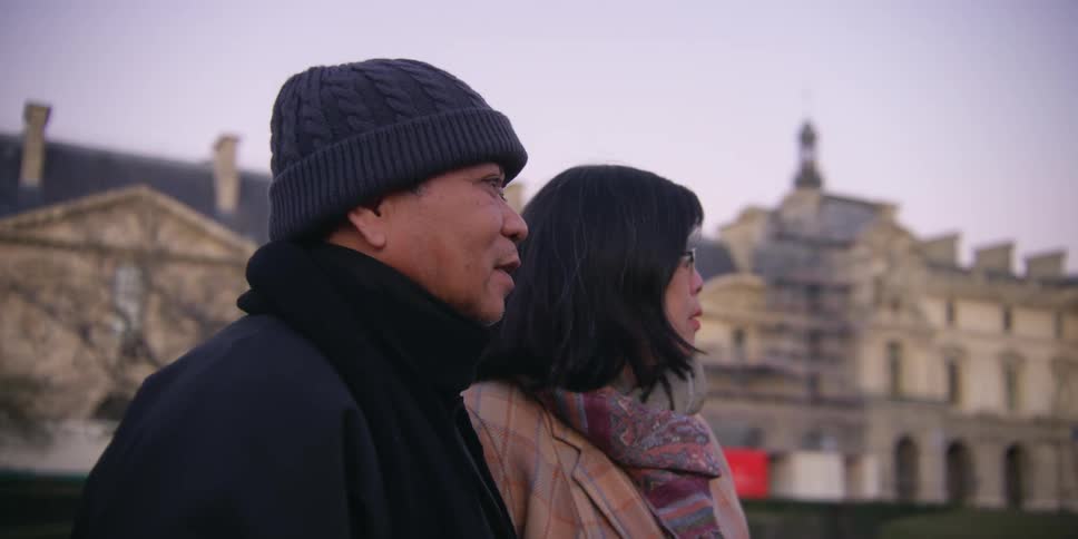 Two people sightseeing stand near old buildings