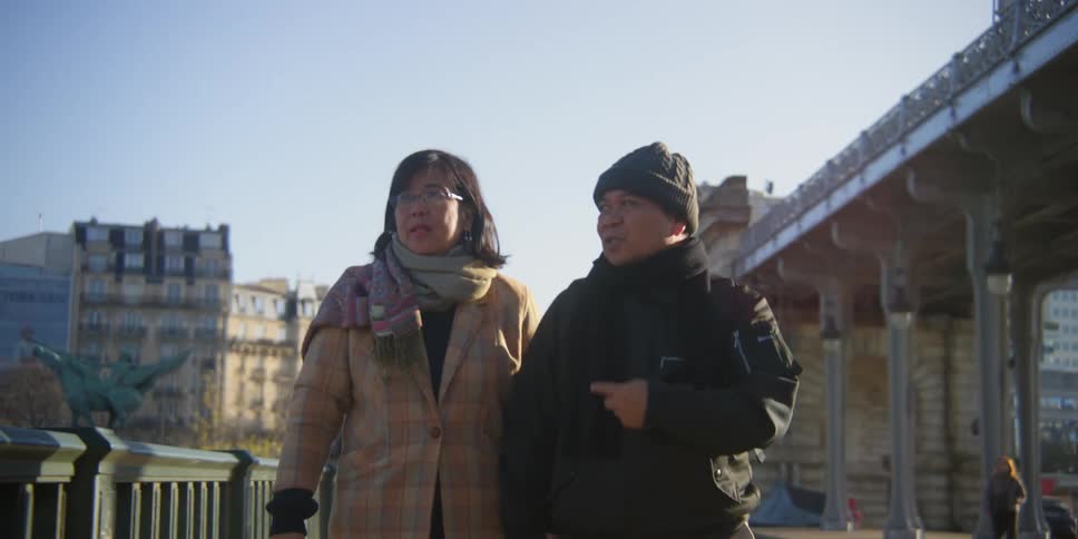 Two people holding hands in warm clothes are walking and talking