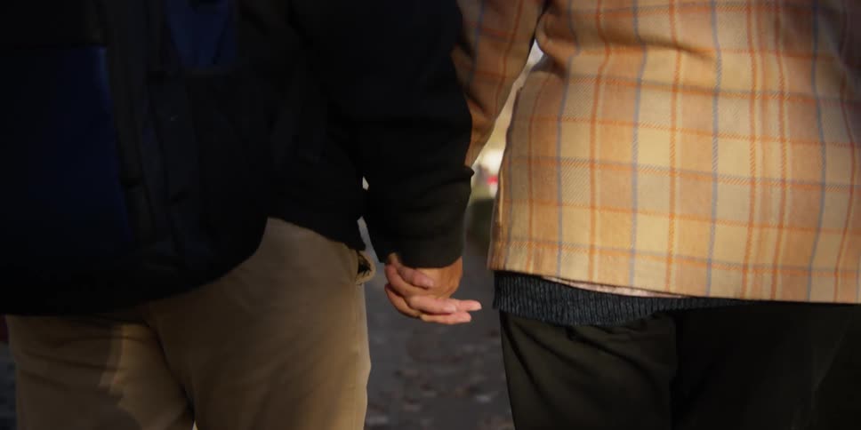 A man and a woman walking on the street while holding arms