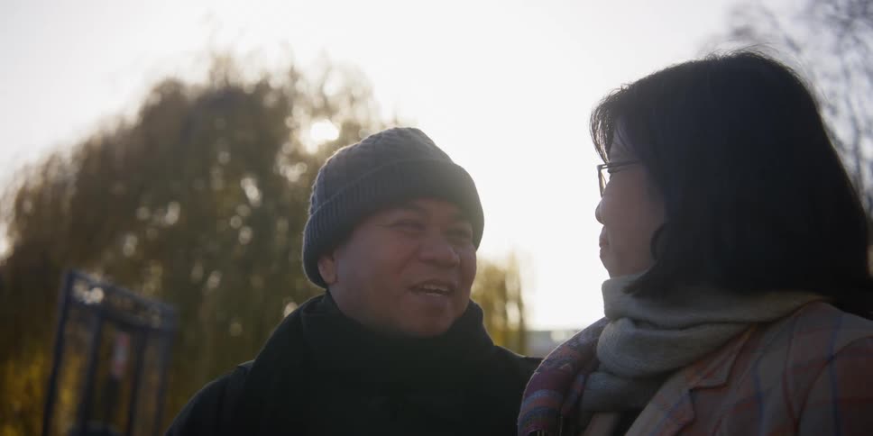 A couple sitting down in a city park smiling and talking to each other