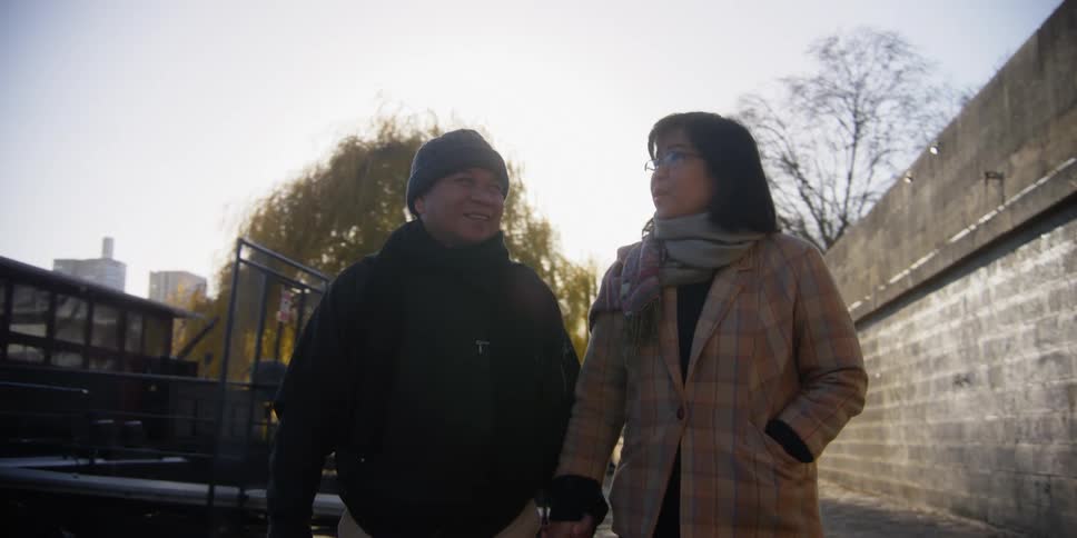 An asian couple walk in a city while holding hands