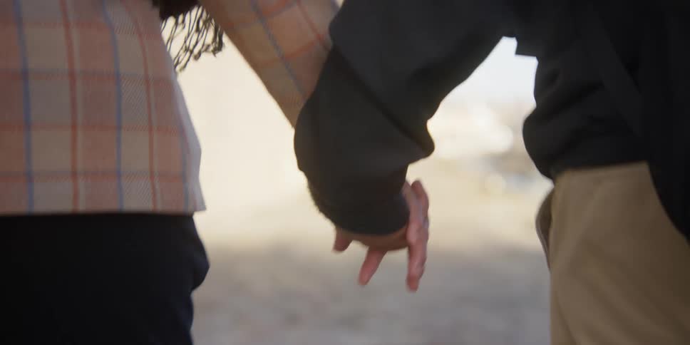 Two people back to back are walking hand in hand