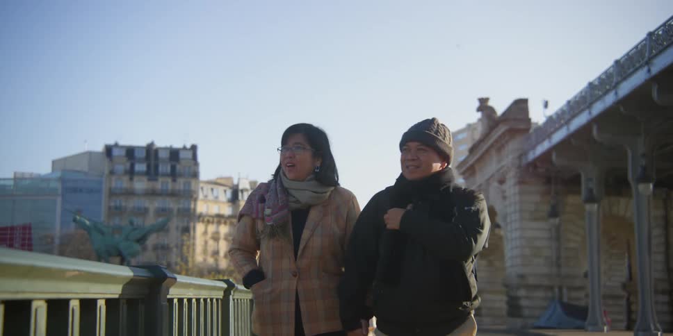 A couple in warm clothes are holding hands while they are walking and pointing with their finger