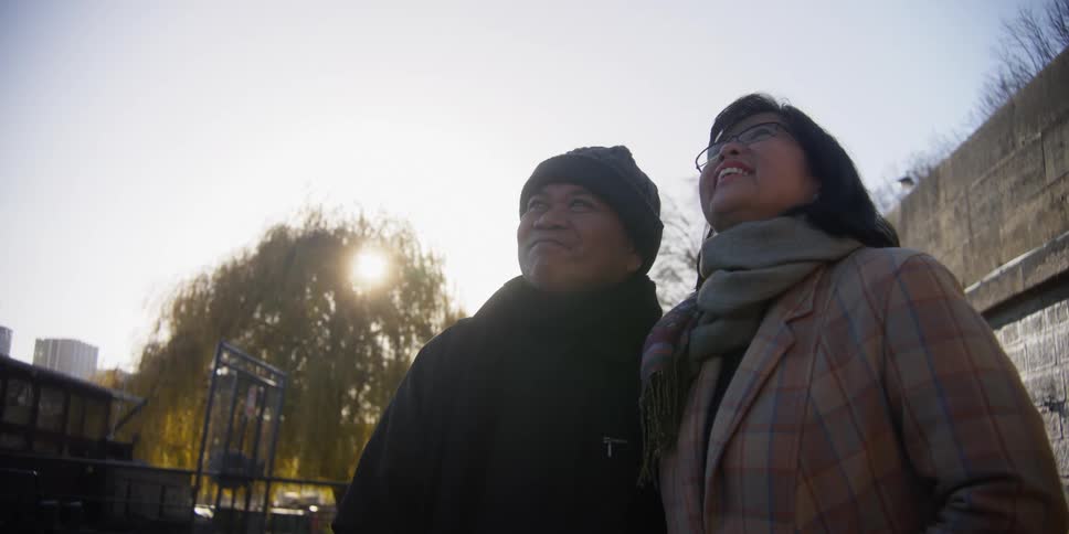 Two asians talk and laugh in a city