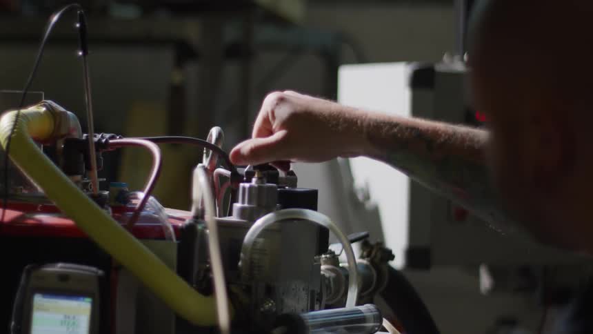 An employee at a business tightens a part of a machine