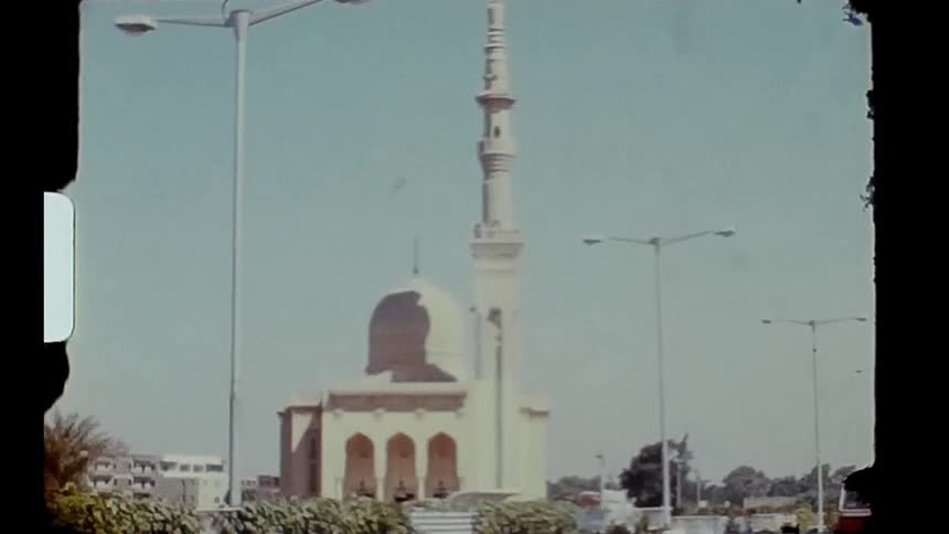 A bus and pedestrian in front of a large mosque