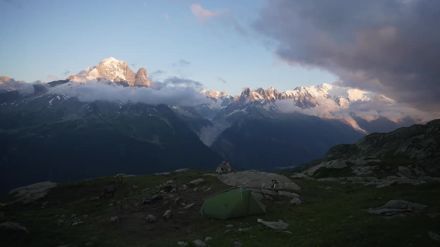 A landscape where there is a tent and delay in the new mountains and clouds