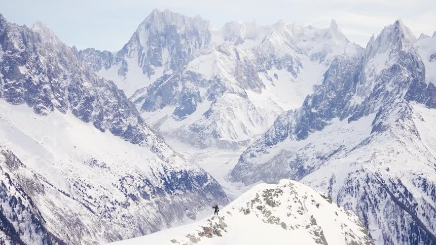 A person is hiking through a snow covered mountain range