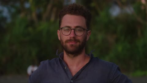 Close up of a bearded man wearing glasses standing outdoors