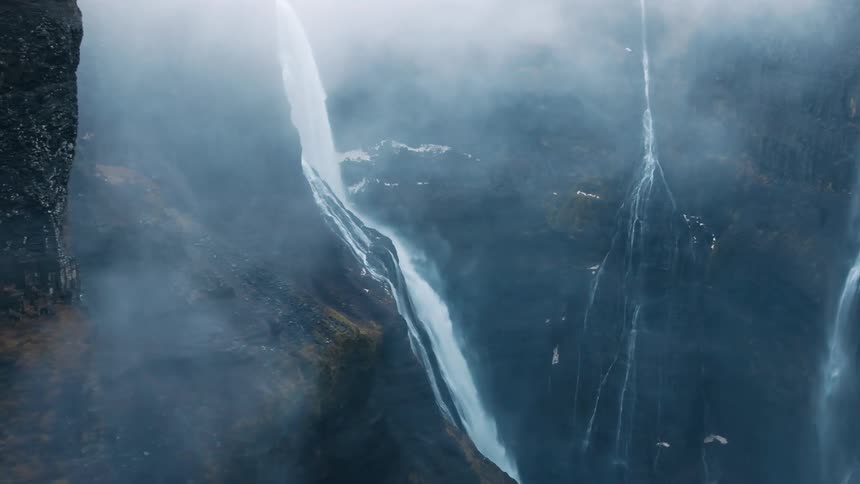 Aerial view of a misty waterfall flowing down a rocky cliff