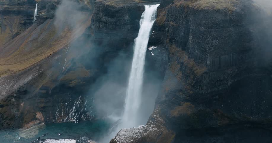 Aerial of a waterfall on a rocky cliff on a cloudy day
