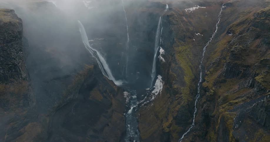 Natural landscape of waterfalls amidst large mountains on a snowy day