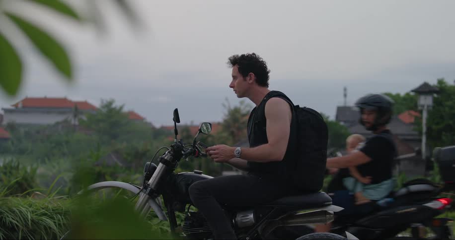 Man standing still and sitting on his motorcycle using his cell phone