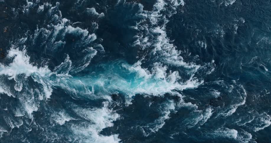 A top view of a river with turbulent waves and white foam