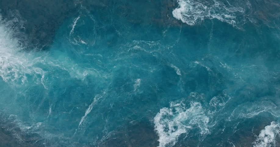 A top view of a river with turbulent waves and white foam