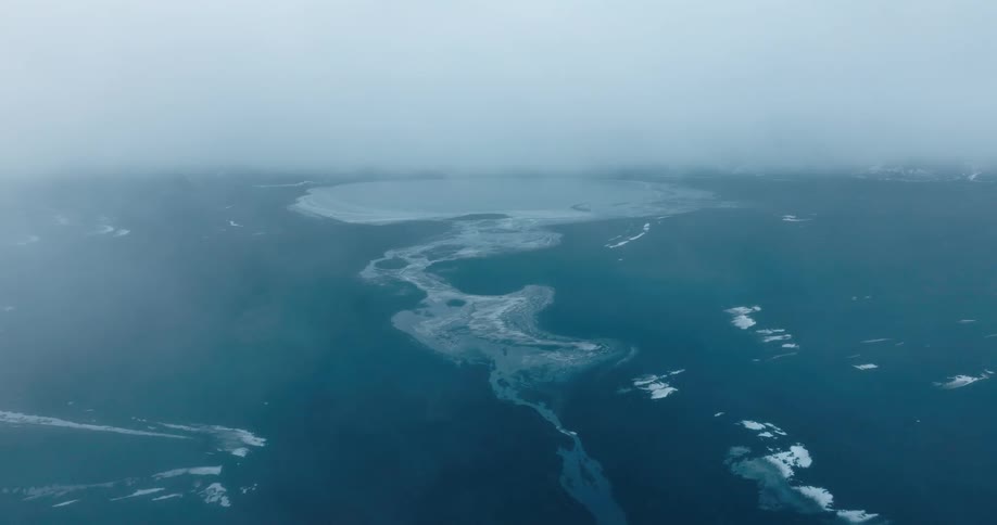 A foggy ocean scene with landmasses and ice formations