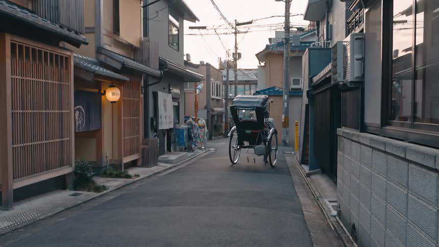 A man wheels a rickshaw through a narrow street
