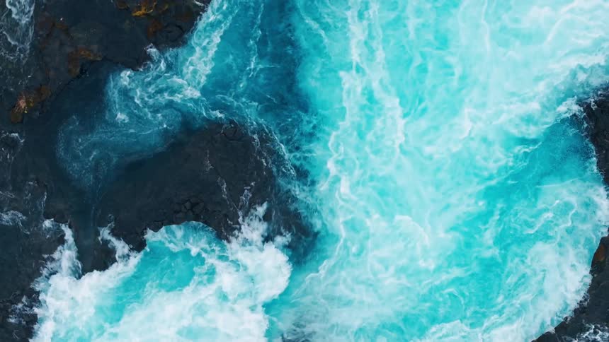 A top view of a river with turbulent waves and white foam