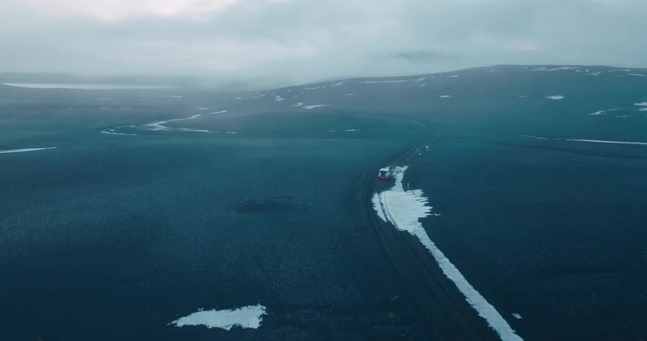 Aerial view of an off road vehicle driving on a desolate landscape
