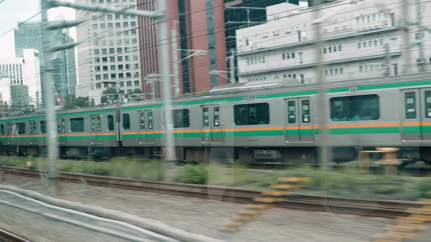 A train with green and orange stripes moving through the city