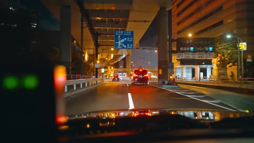 Vehicles passing under an overpass at night in a metropolis