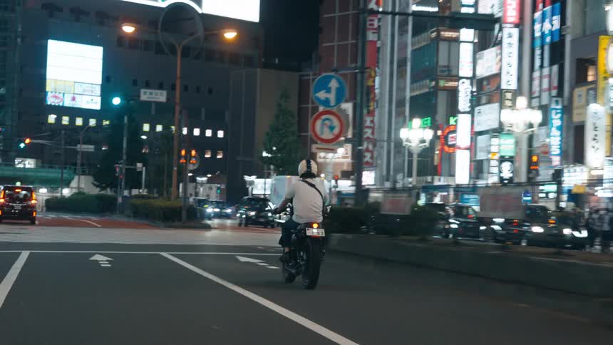 A person riding a motorcycle in the city a night
