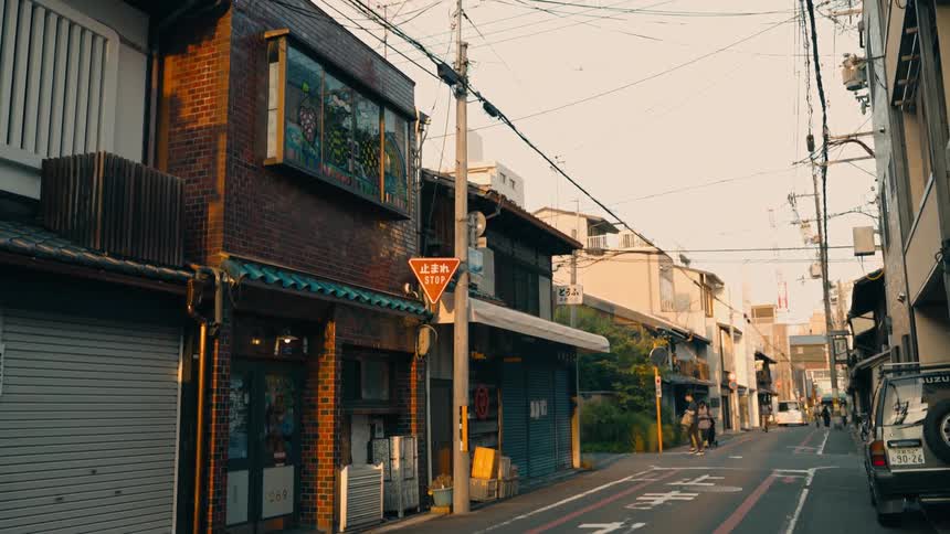 Buildings and people walking around on a street at sunset in Kyoto